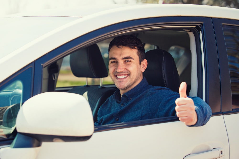 Cheerful Man Driving A Car — Fast & Affordable Car Hires in Bilinga, QLD