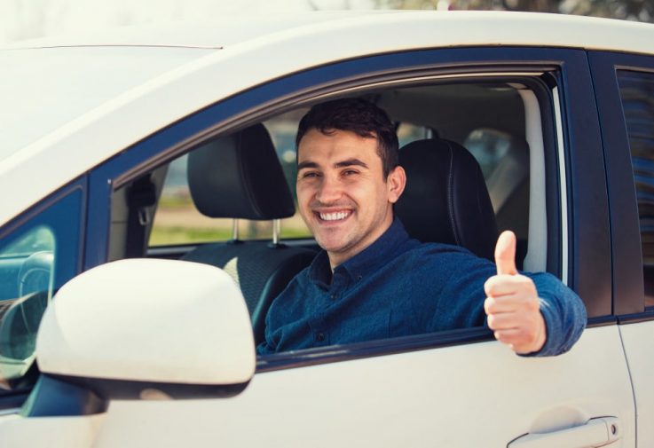 Cheerful Man Driving A Car — Fast & Affordable Car Hires in Bilinga, QLD